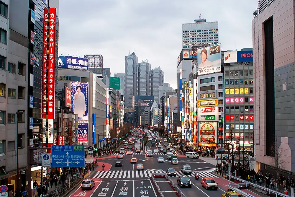 Ulice Shinjuku četvrti u Tokiju s neonskim reklamama i japanskim natpisima u sumrak